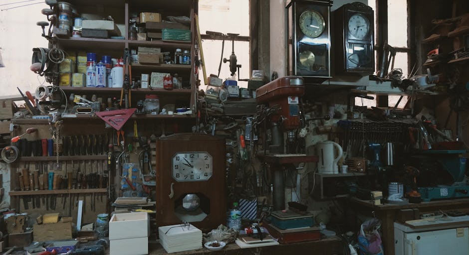 A cluttered vintage workshop featuring antique clocks, tools, and shelves filled with jars and boxes.